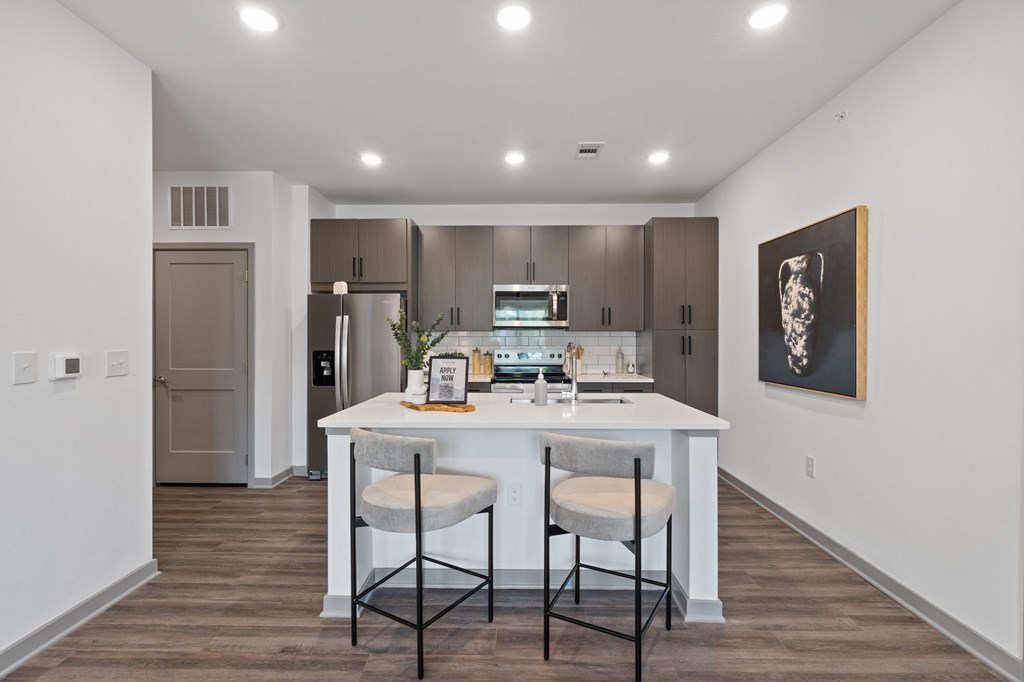 A kitchen with a white countertop and two chairs.