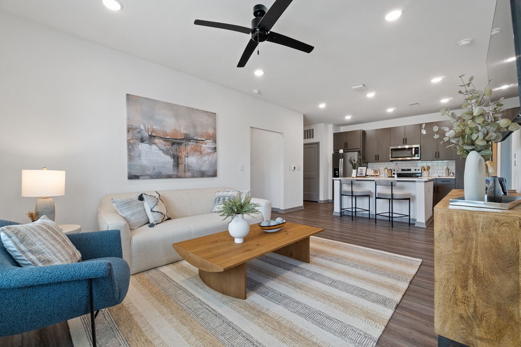 A living room with a blue chair, a white couch, and a painting on the wall.