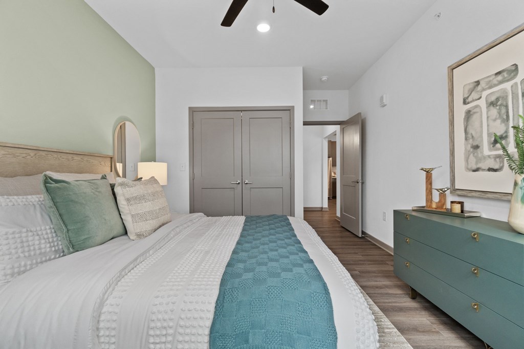 A bedroom with a large bed and a green dresser.