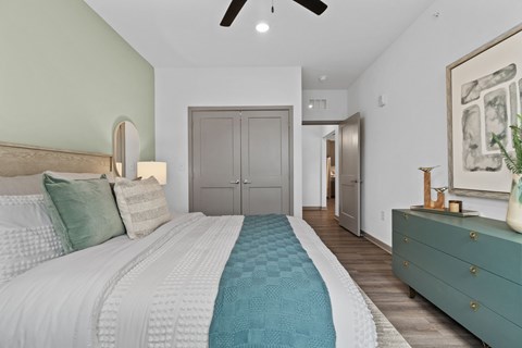 A bedroom with a large bed and a green dresser.