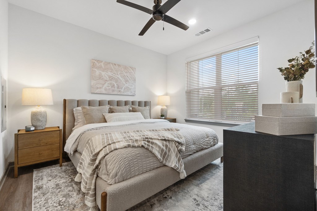 A bedroom with a large bed and a ceiling fan.