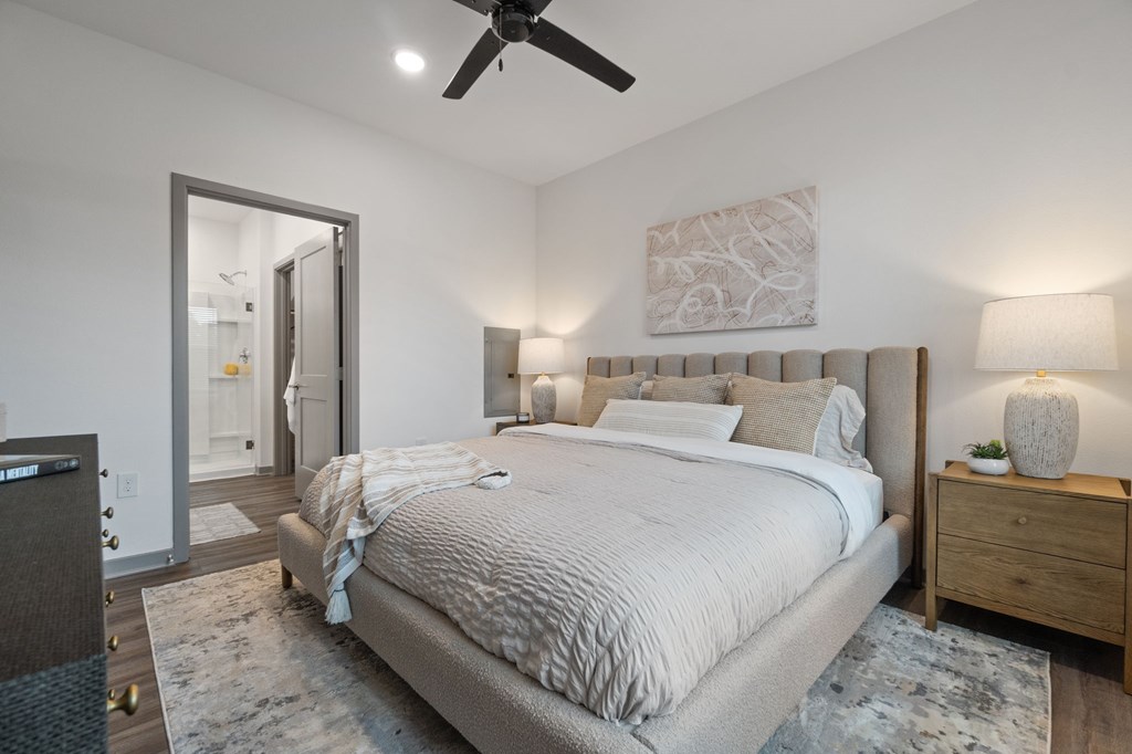 A bedroom with a large bed, a ceiling fan, and a rug on the floor.