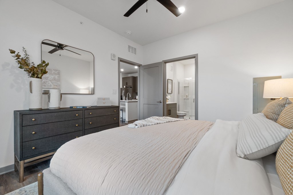 A bedroom with a large bed and a dresser with a mirror above it.