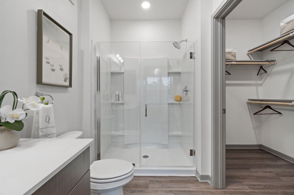 A white toilet sits in a bathroom next to a walk-in shower.