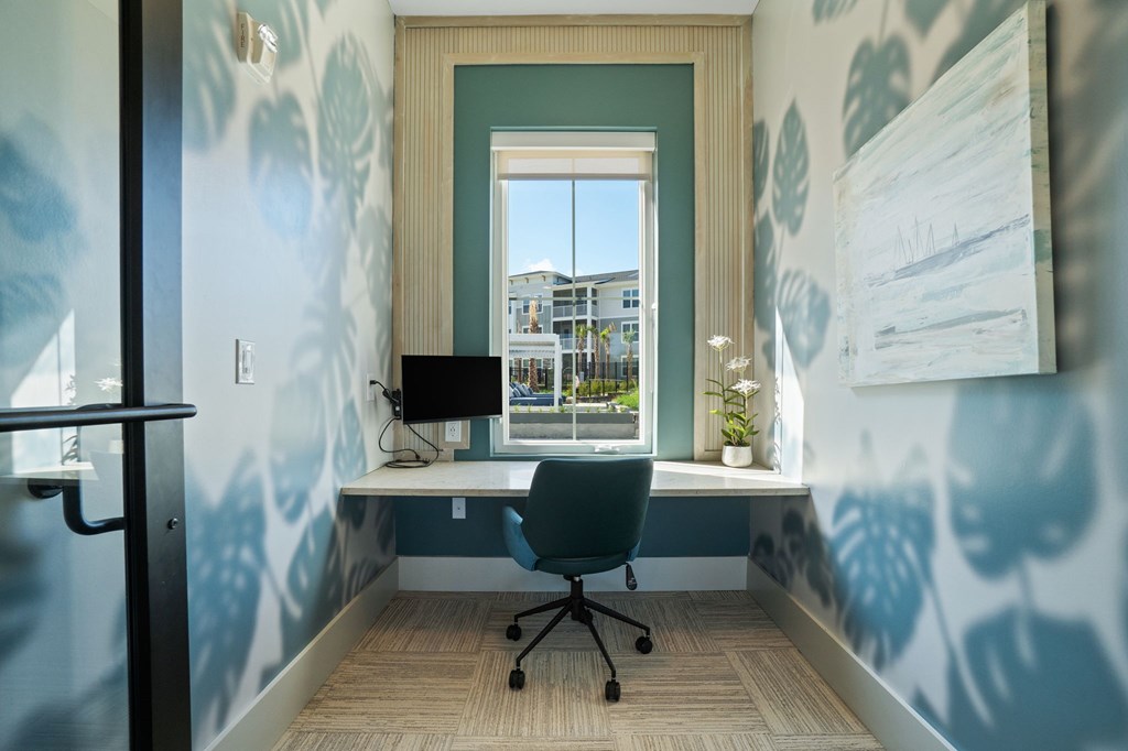 A room with a desk and a window overlooking a building.