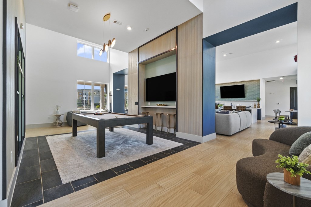 A modern living room with a dark wood floor and a large TV.