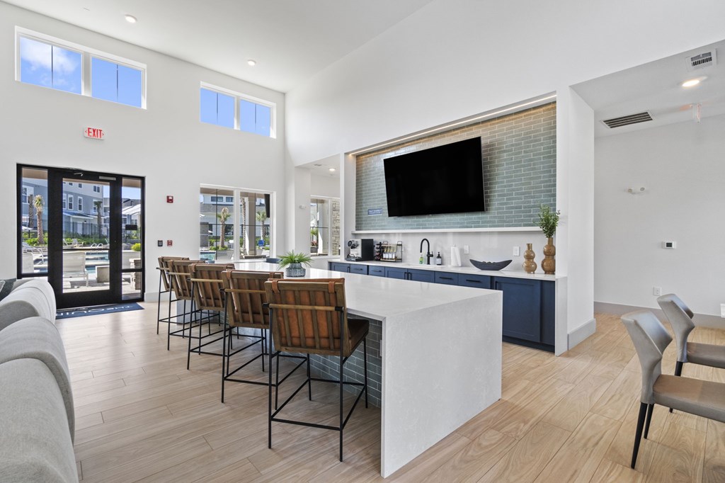 A modern kitchen with a bar and chairs.