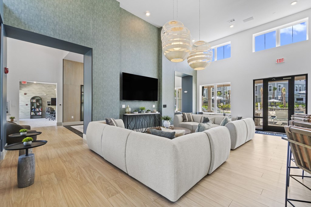 A modern living room with a long white couch and a television mounted on the wall.