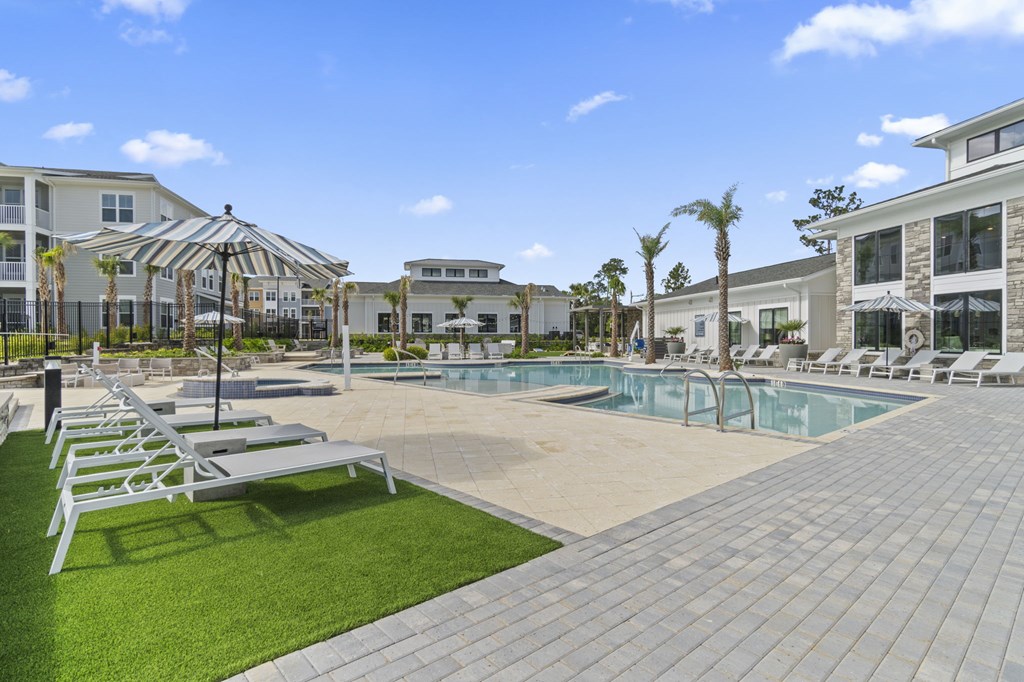 A large outdoor swimming pool surrounded by lounge chairs and palm trees.