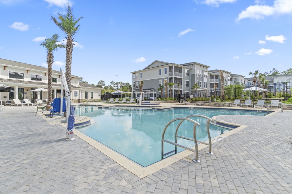 A swimming pool surrounded by a brick patio and palm trees.