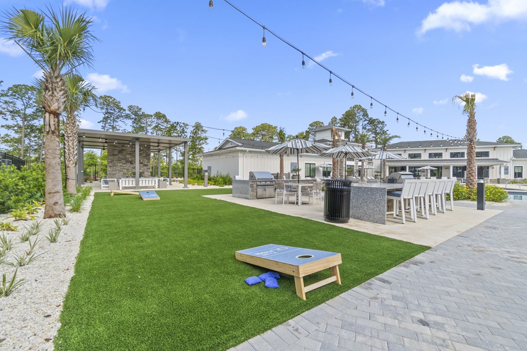 A backyard with a lawn, a table and chairs, and a pool.