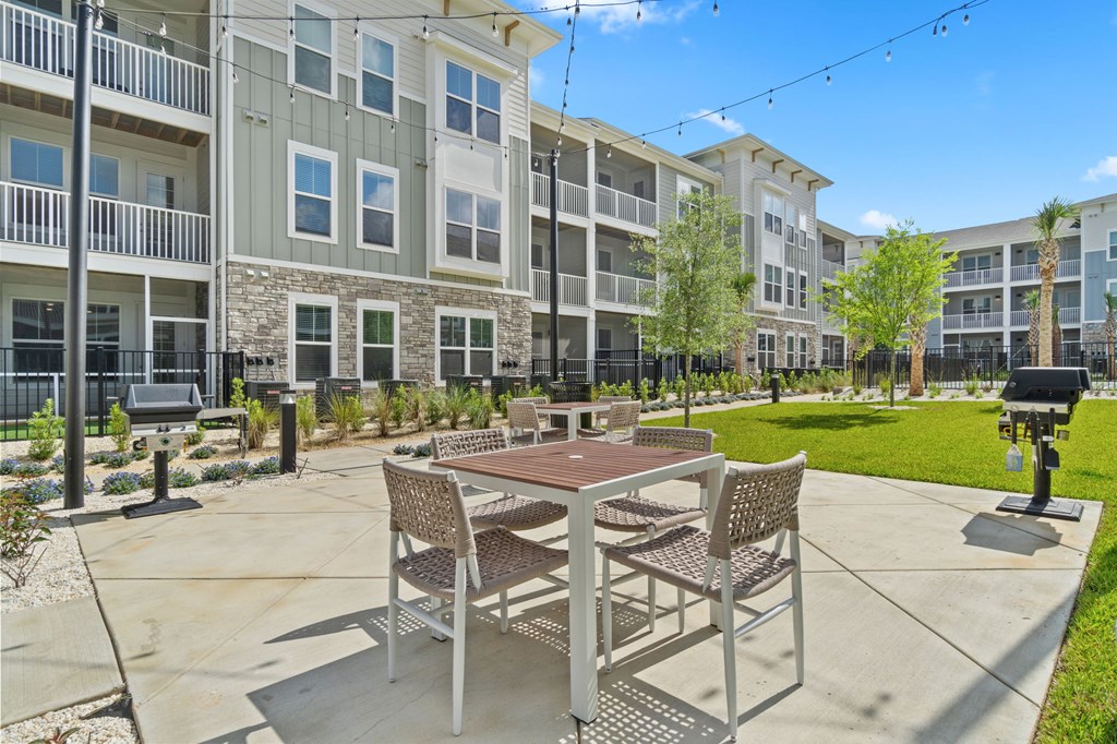 A patio with a table and chairs is surrounded by apartment buildings.