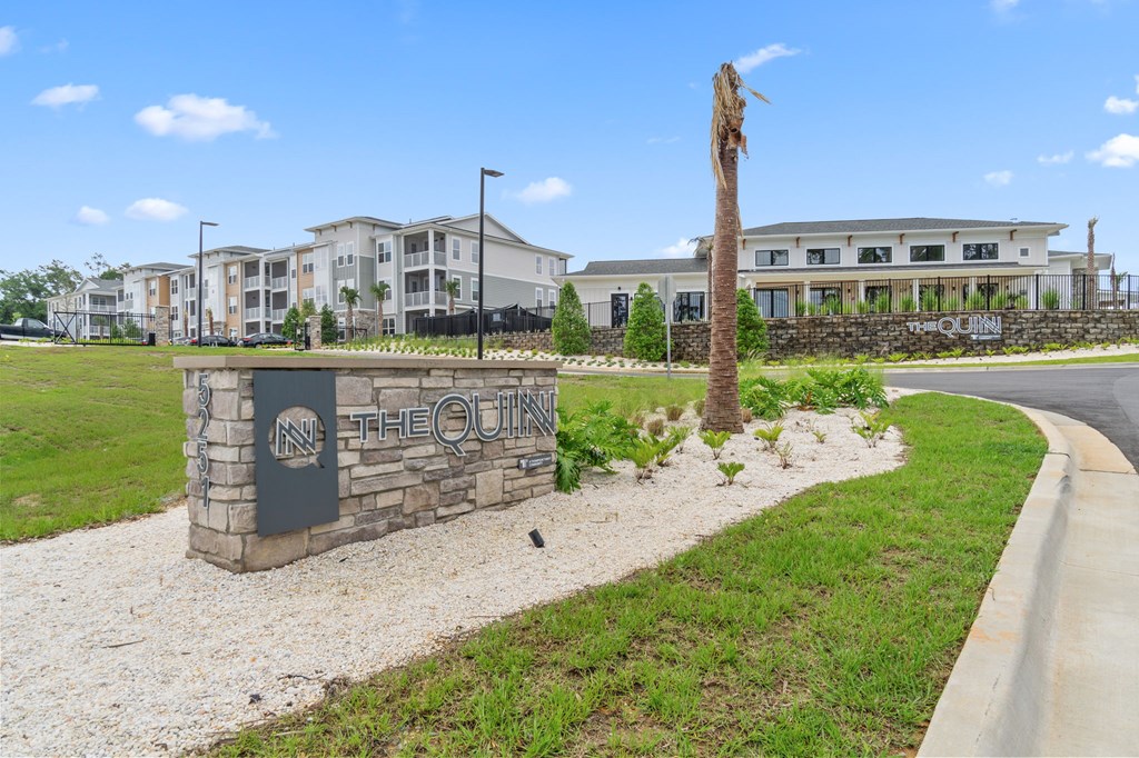 A sign that says "The Quin" stands in front of a building.