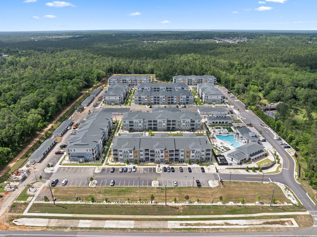 A large, modern building complex surrounded by trees and a parking lot.
