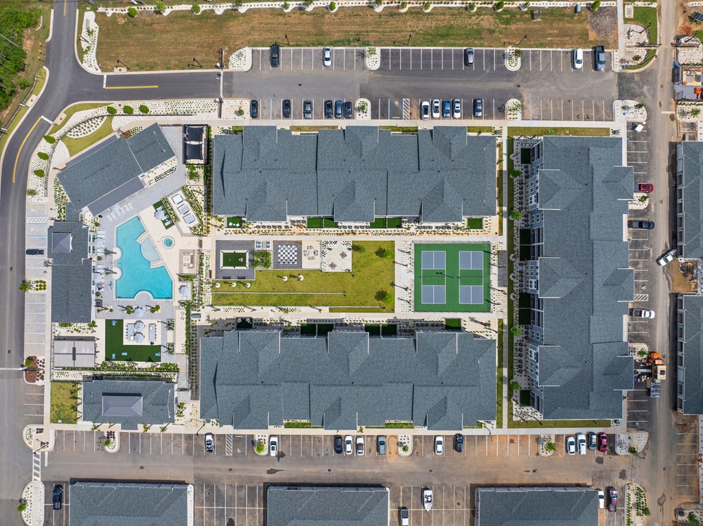 A large building complex with a tennis court in the middle.