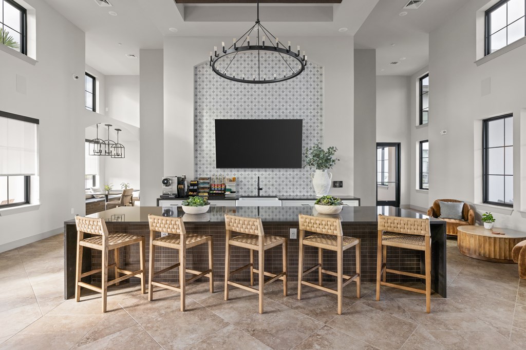 A modern kitchen with a large island and chairs.