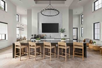 A modern kitchen with a large island and chairs.