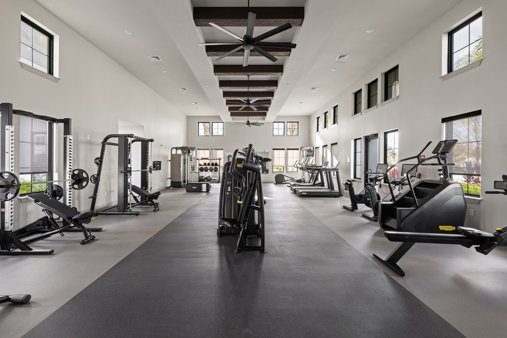 A spacious gym with a variety of equipment and a long mirrored wall.