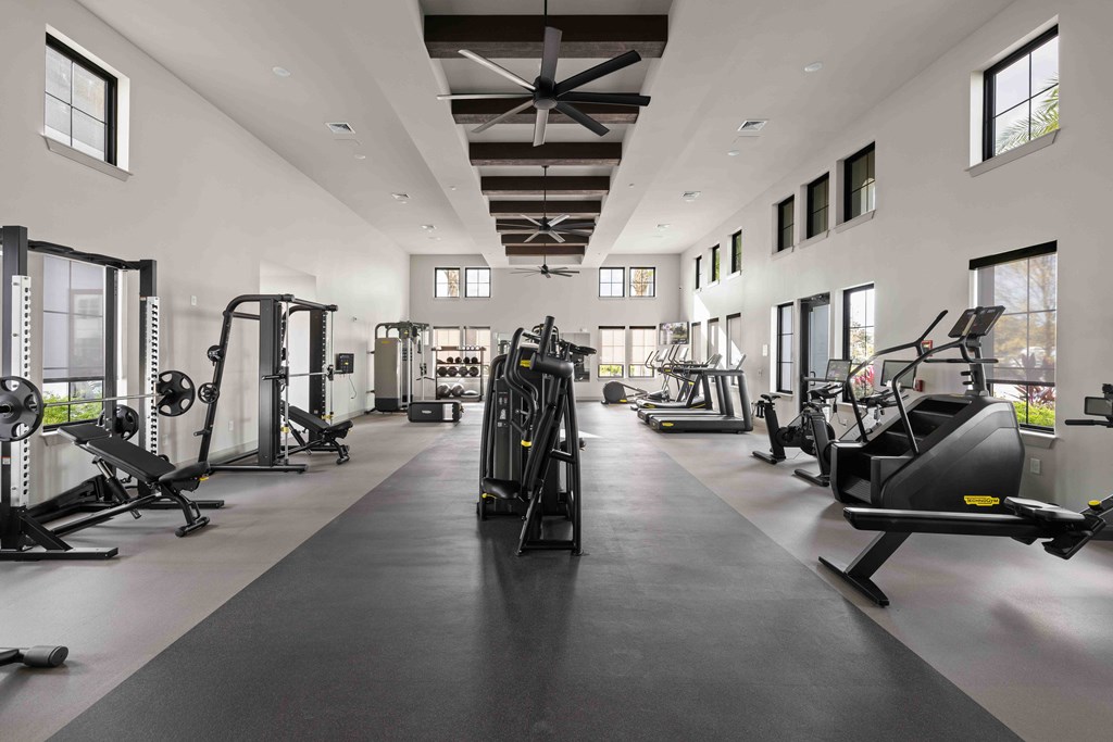 A spacious gym with a variety of equipment and a long mirrored wall.