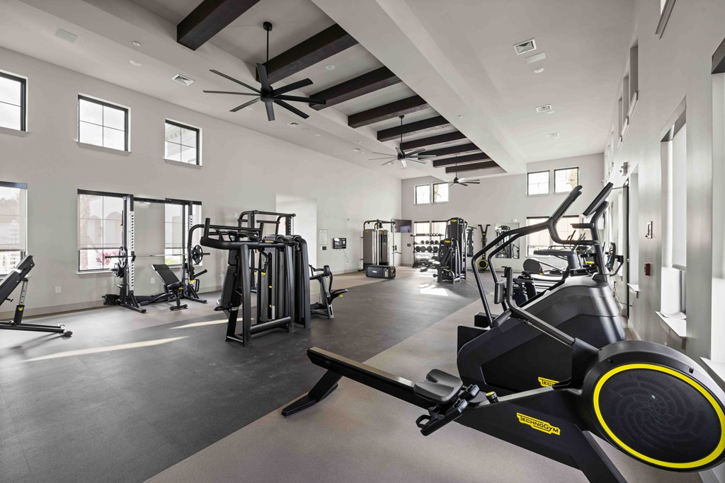 A spacious gym with a variety of equipment including treadmills, weights, and a rowing machine.