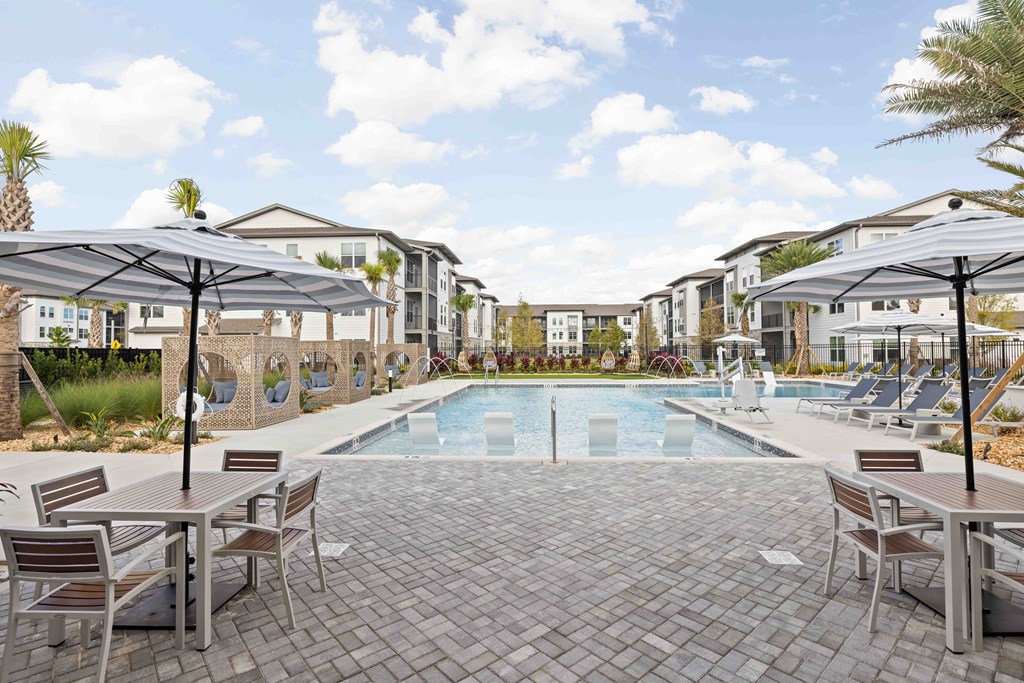 A pool surrounded by chairs and umbrellas in a resort-like setting.