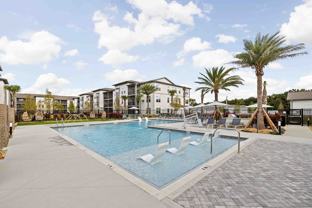 A large swimming pool surrounded by palm trees and lounge chairs.