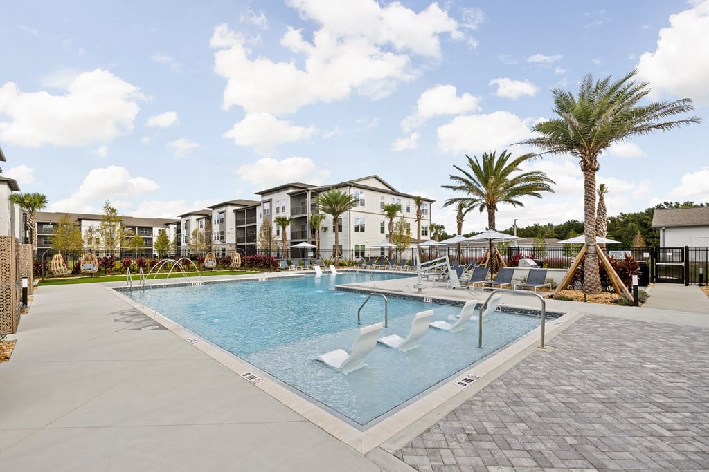 A large swimming pool surrounded by palm trees and lounge chairs.