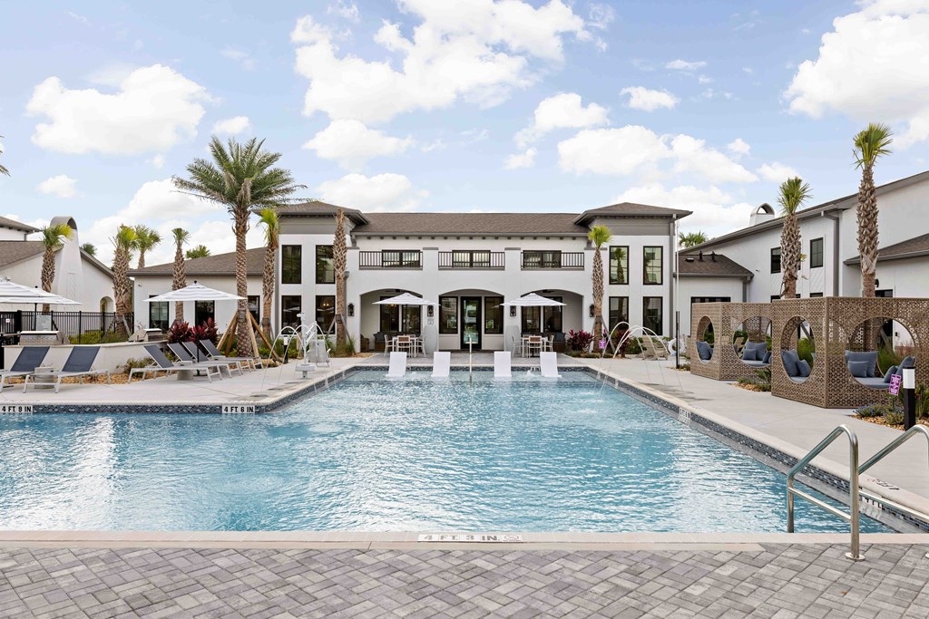 A large swimming pool in front of a building with palm trees.