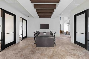 A conference room with a table surrounded by chairs.