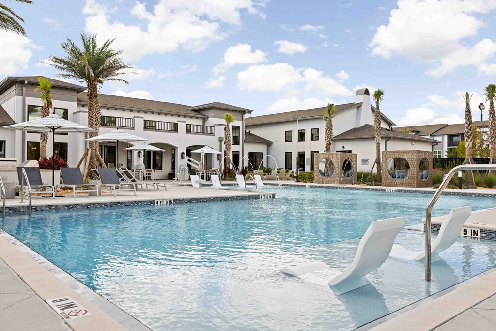 A pool with chairs and a building in the background.
