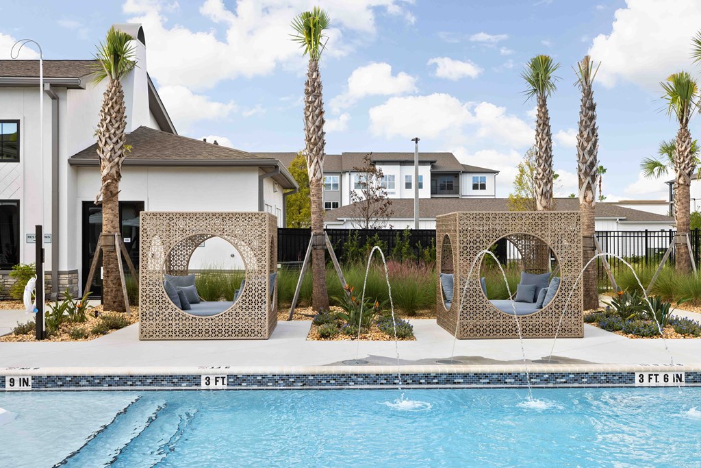 A pool with a white building and palm trees in the background.