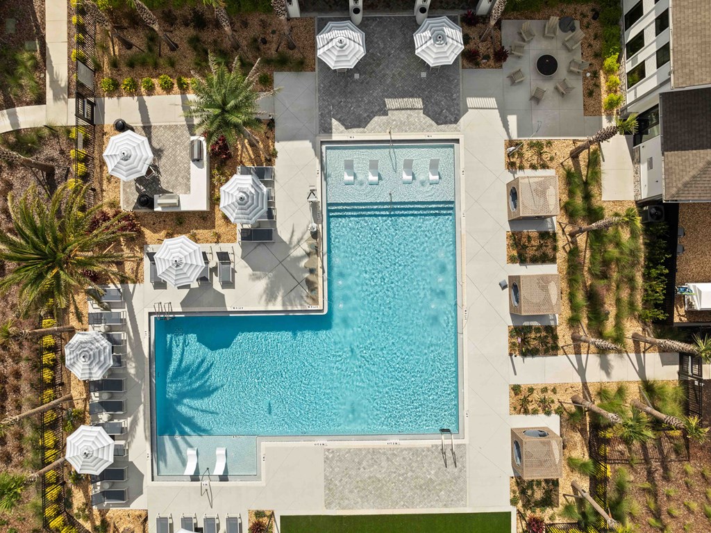 An aerial view of a swimming pool surrounded by lounge chairs and umbrellas.