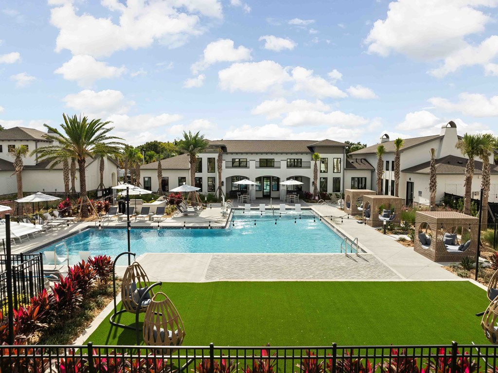 A large swimming pool surrounded by a grassy area and palm trees.