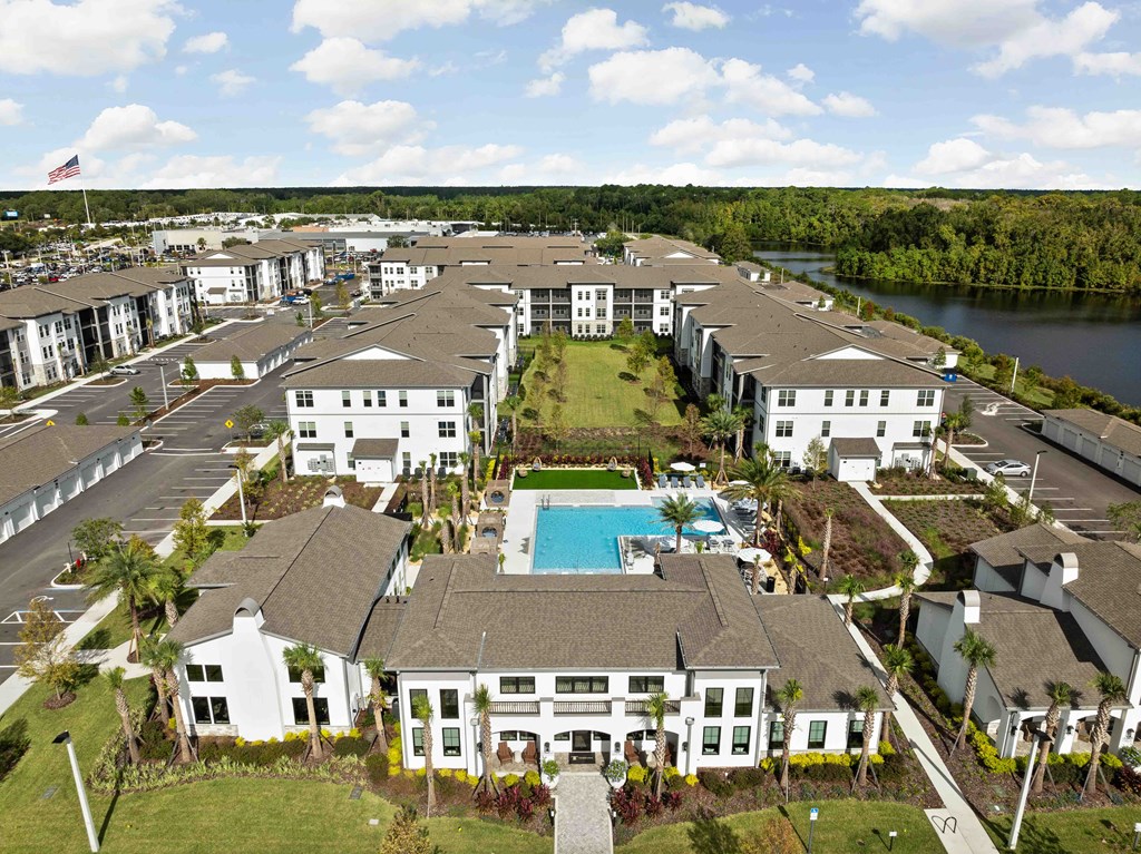 A large white building with a pool in the middle of a grassy area.