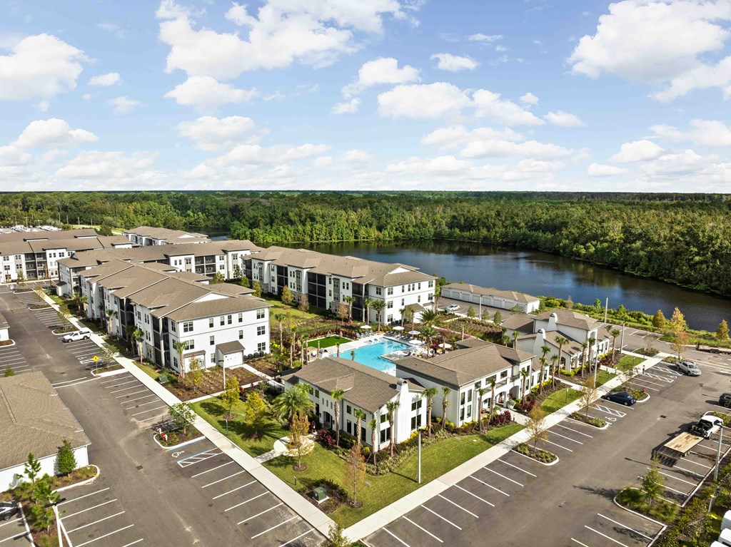 A large apartment complex with a swimming pool and a river in the background.