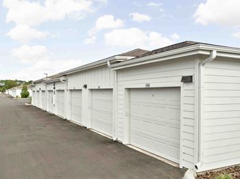 A long row of white garages are lined up on a street.