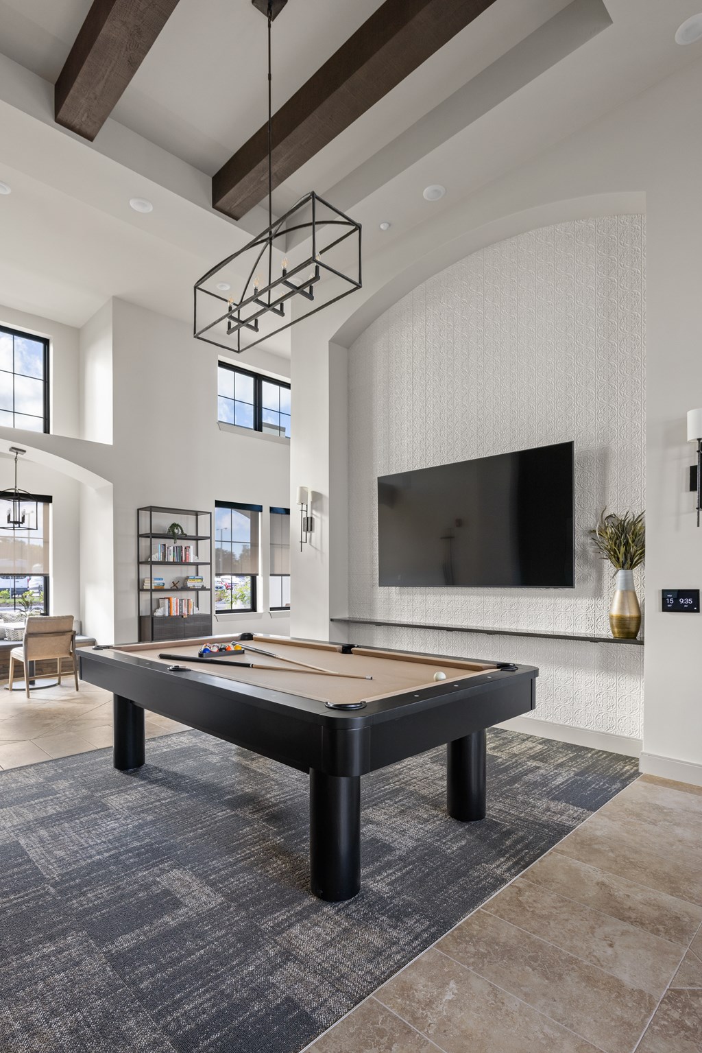 A pool table is in the middle of a room with a television and a chair.