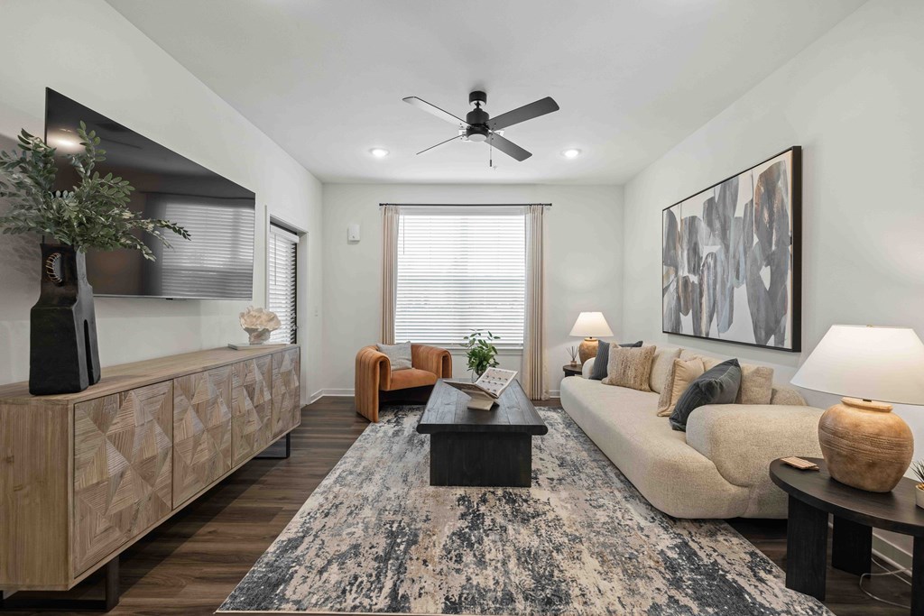 A living room with a rug, a couch, a coffee table, and a ceiling fan.