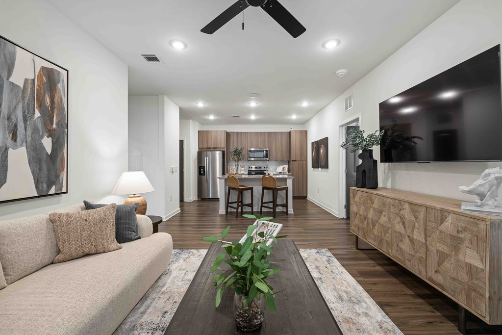 A living room with a couch, a table, a plant, and a painting on the wall.
