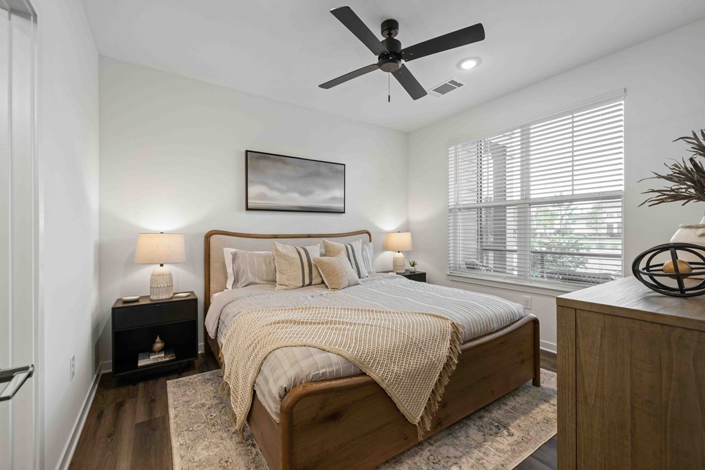 A bedroom with a bed, nightstand, and a ceiling fan.