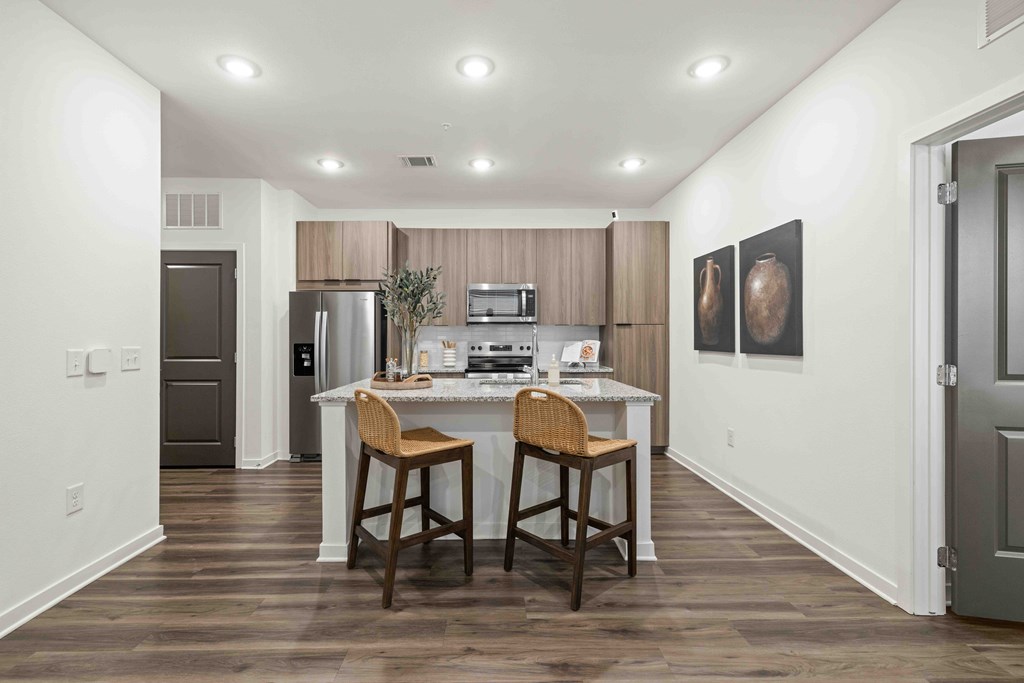 A kitchen with a white countertop and brown bar stools.