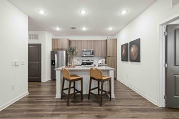 A kitchen with a white countertop and brown bar stools.