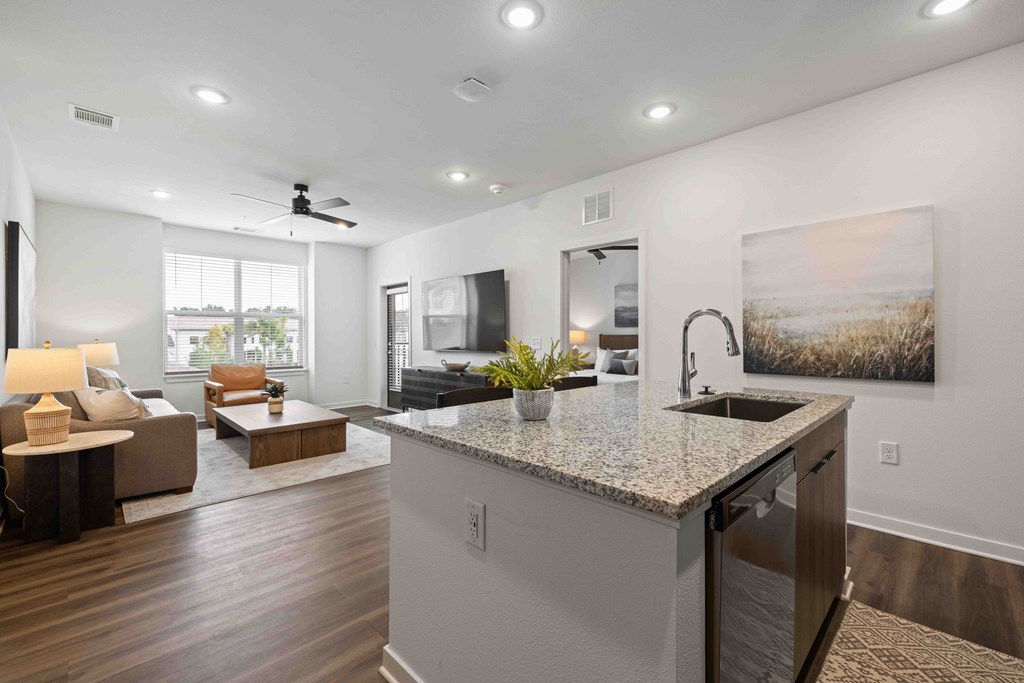 A modern kitchen with a large island and a living area with a sofa and a coffee table.