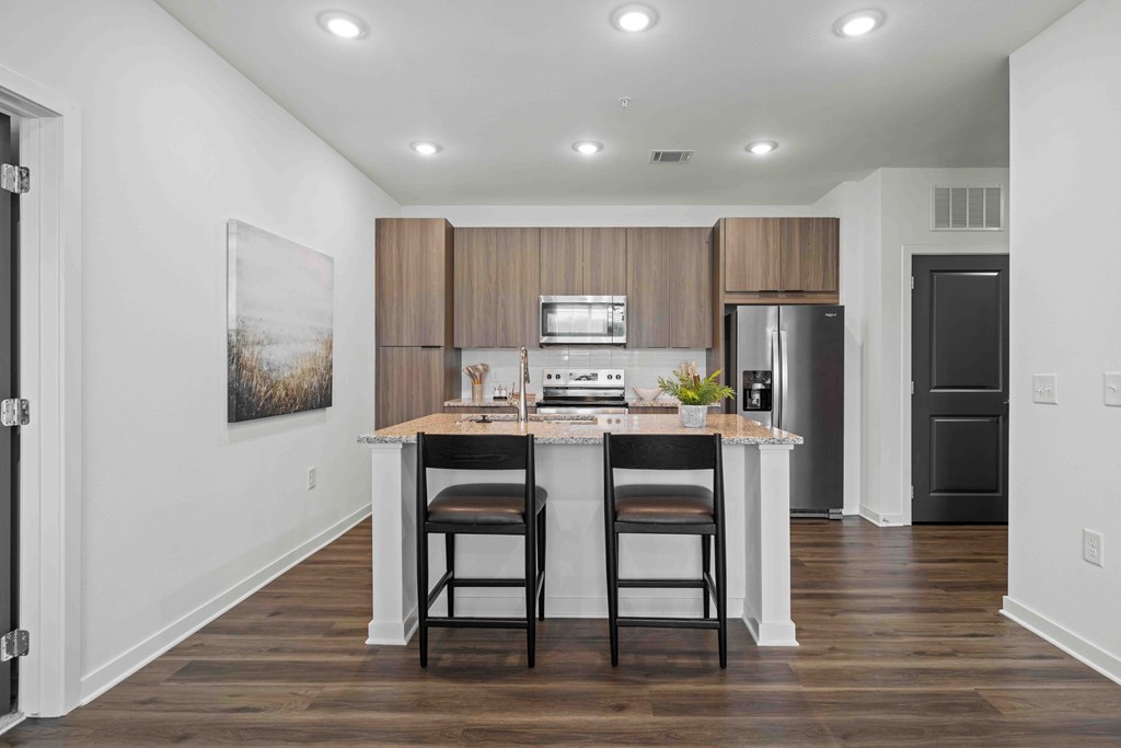 A kitchen with a table and chairs in front of a refrigerator.