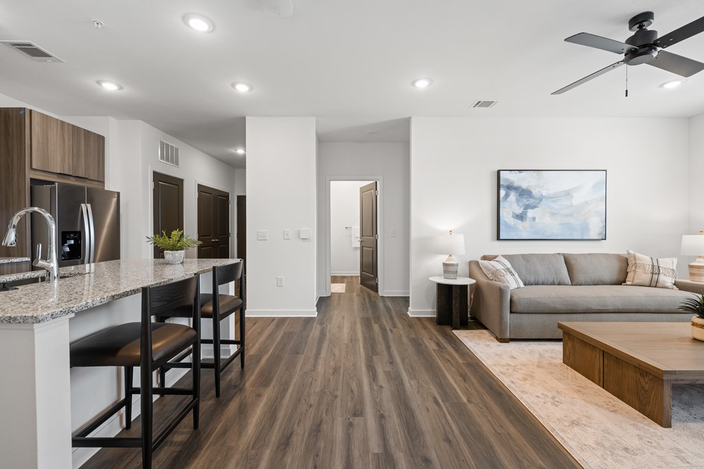A modern kitchen with dark wood floors and white walls.