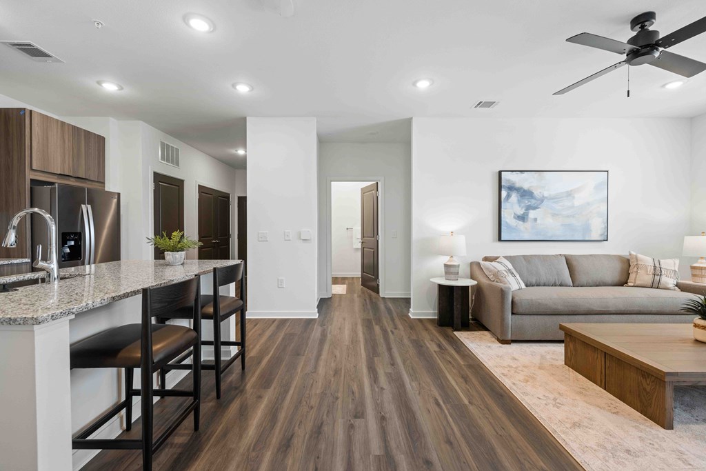 A modern kitchen with dark wood floors and a white ceiling fan.