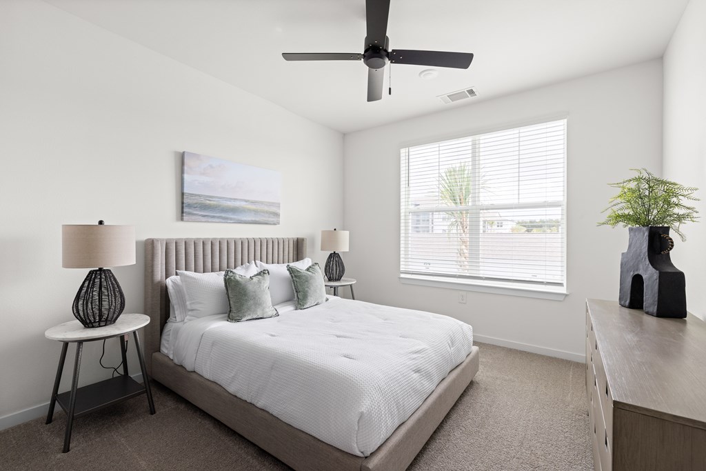 A bedroom with a bed, a ceiling fan, and a window with blinds.