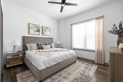 A bedroom with a large bed and a ceiling fan.