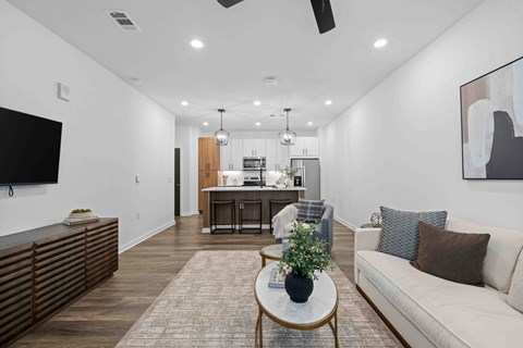 A living room with a white couch, a coffee table, and a television.