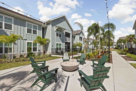 A sunny day at a residential area with green chairs and a fountain.